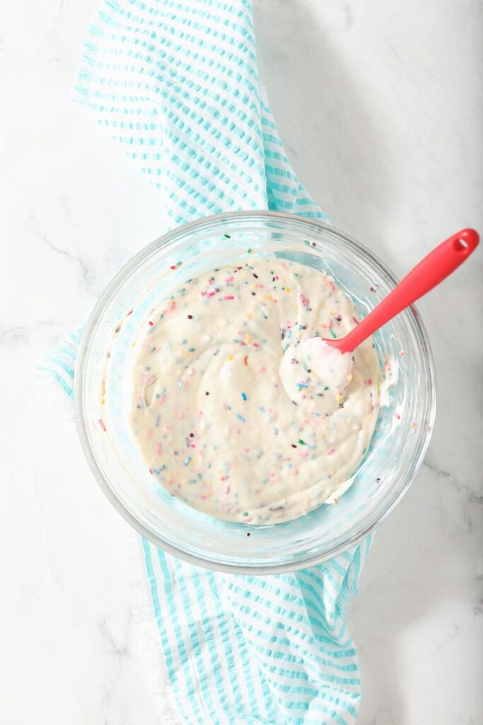 A bowl of a dessert dip with a red spatula in it