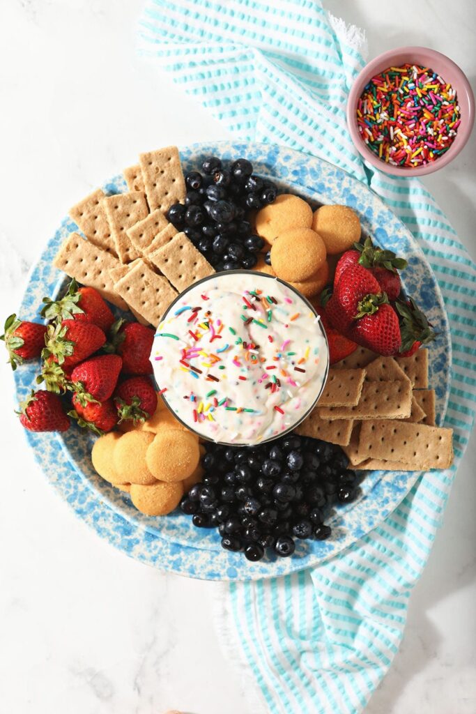 Funfetti Dip in a bowl with on a platter of crackers, cookies and fresh fruit