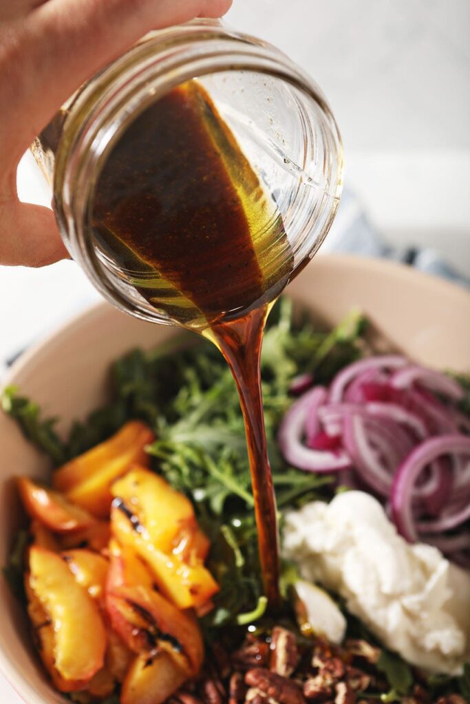 Homemade balsamic vinaigrette pours on top of an arugula salad