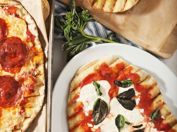 Three grilled pizzas on platters