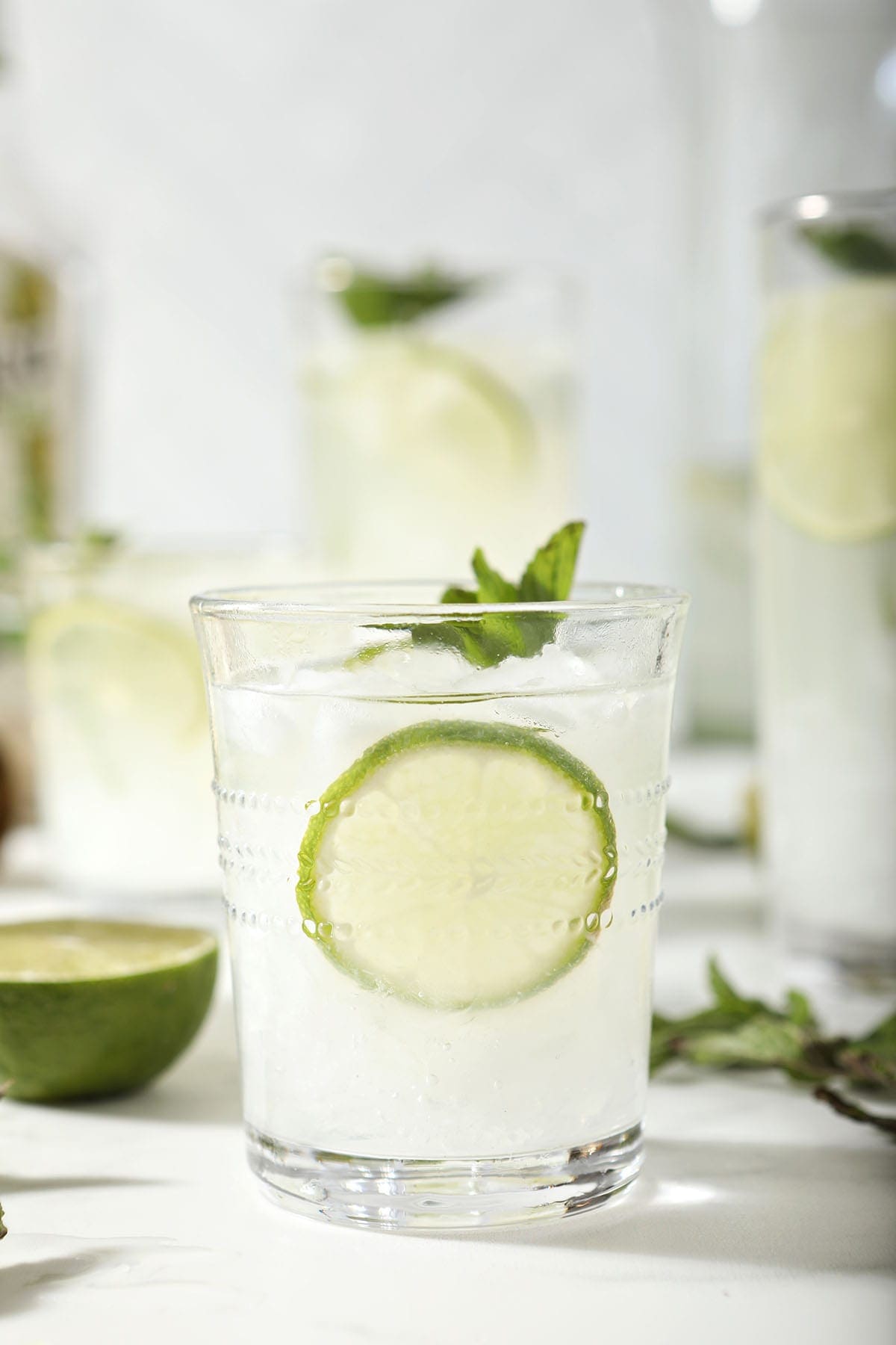 A mojito in a clear glass with lime rounds and mint