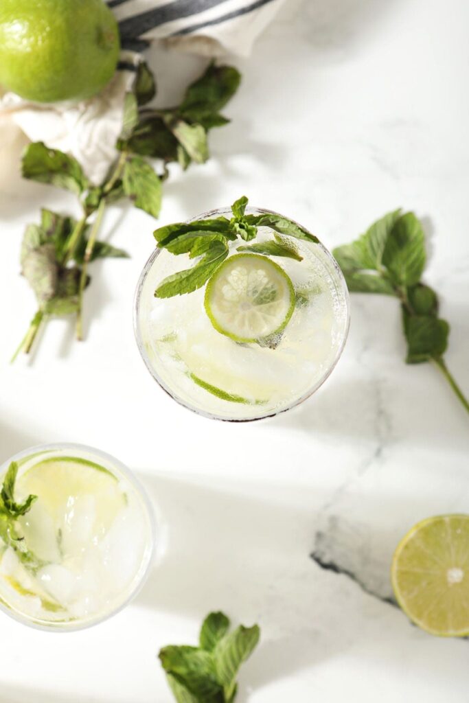 Two mojitos with extra mint and lime garnishes