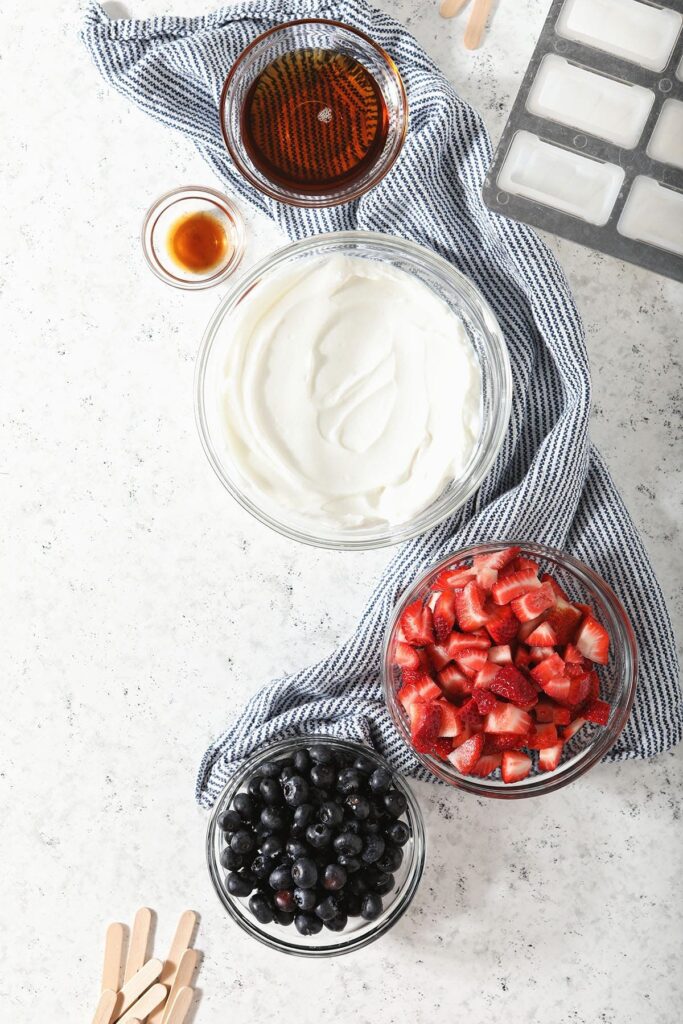 Ingredients for homemade yogurt popsicles in bowls on marble