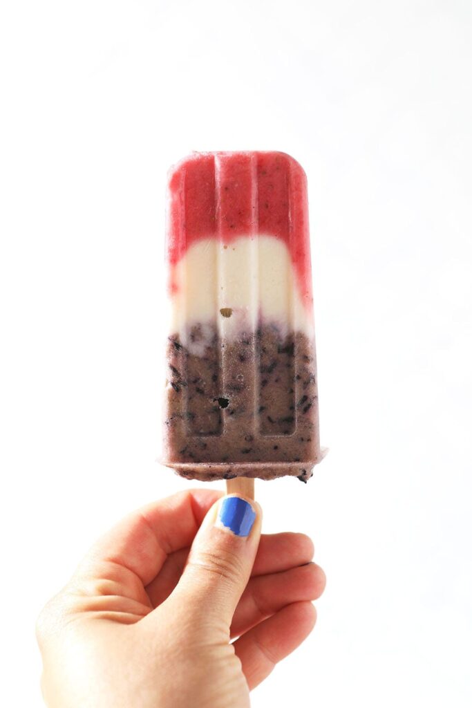 A hand holds a Red White and Blue Popsicle