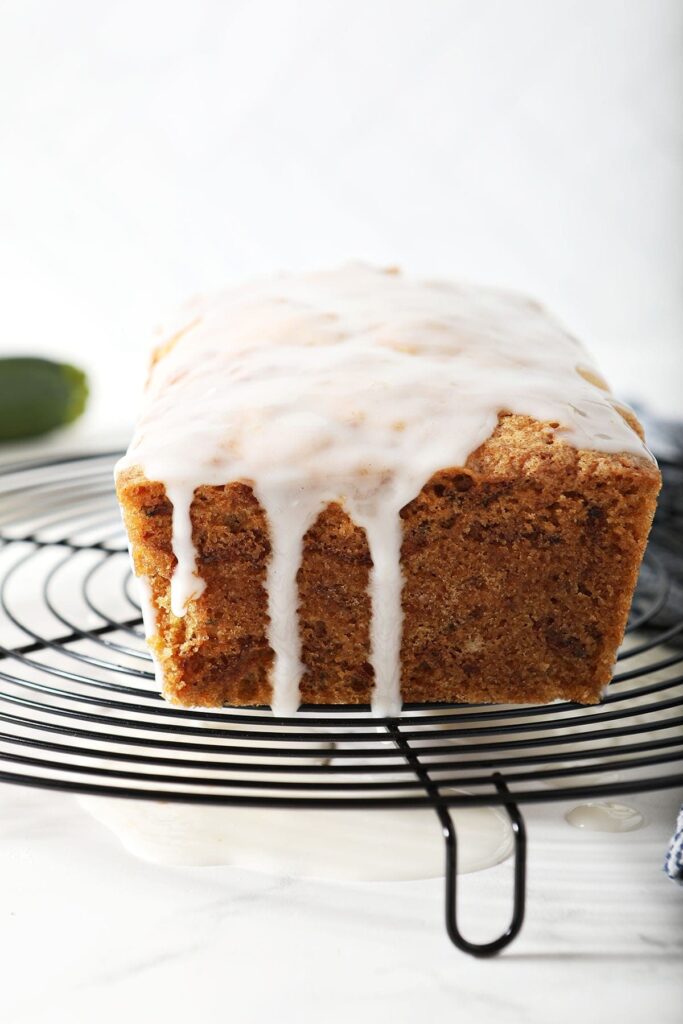 Lemon icing drips down the side of bread on a cooling rack