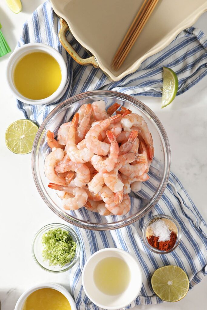 Raw shrimp in a bowl with seasonings in other bowls