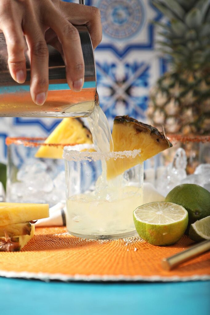 A cocktail shaker pours a drink into a glass