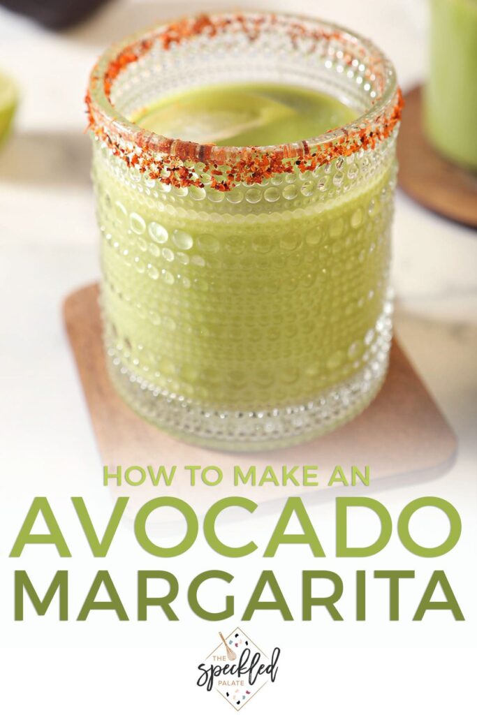 A green cocktail on a wooden coaster with a tajin rim with the text how to make an avocado margarita