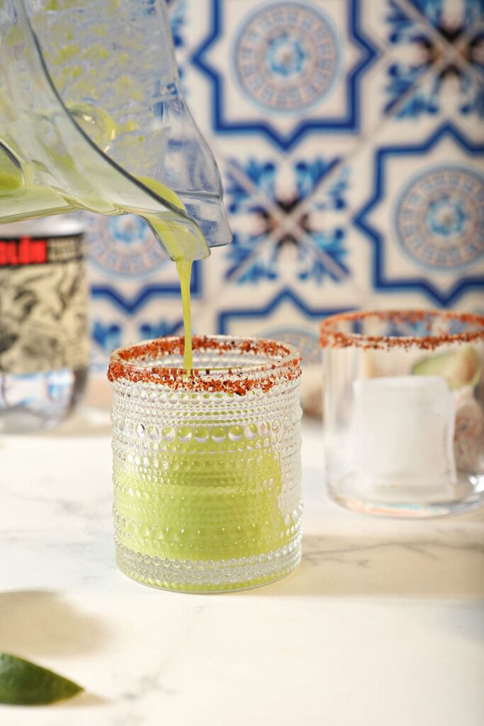 An avocado cocktail pours from a blender into a glass