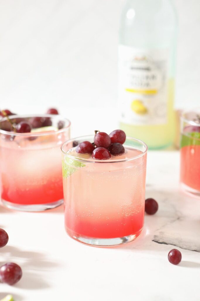 Two grape shrub cocktails on marble with grape garnishes