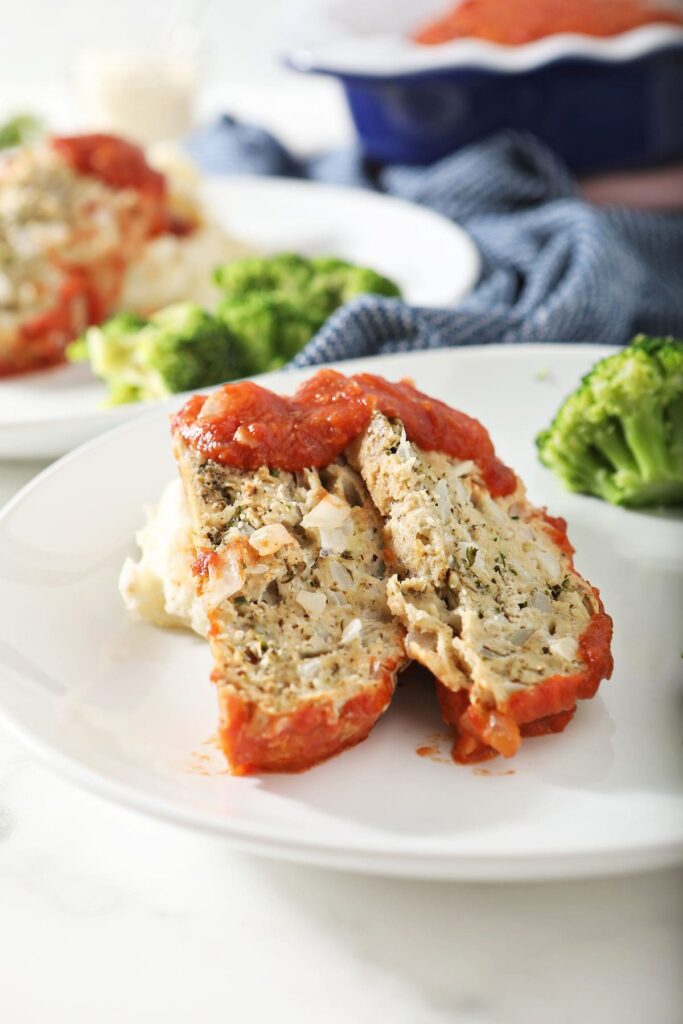 Two slices of chicken meatloaf on top of mashed potatoes