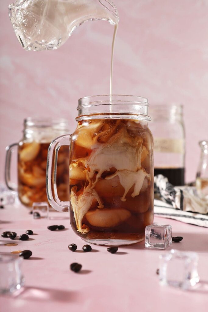 Homemade vanilla sweet cream pours into a glass of cold brew