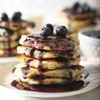 A stack of pancakes with blueberries and syrup