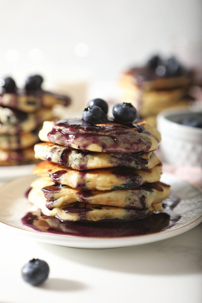 A stack of pancakes with blueberries and syrup