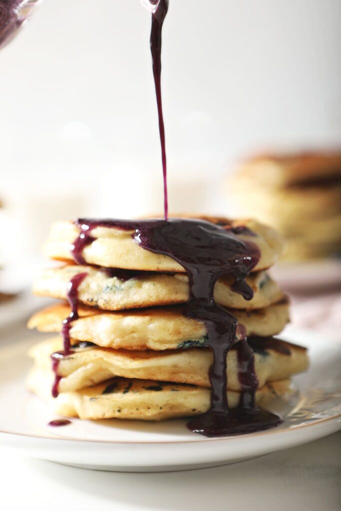 Syrup pours onto a stack of pancakes