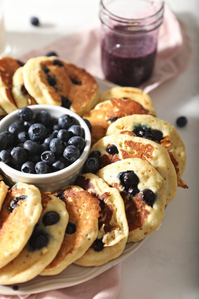 A plate of blueberry pancakes with fresh blueberries