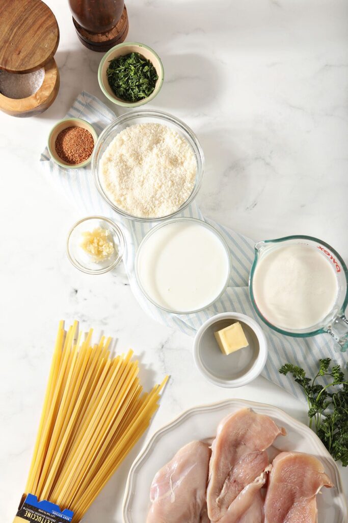 Ingredients to make a pasta dish in bowls on marble