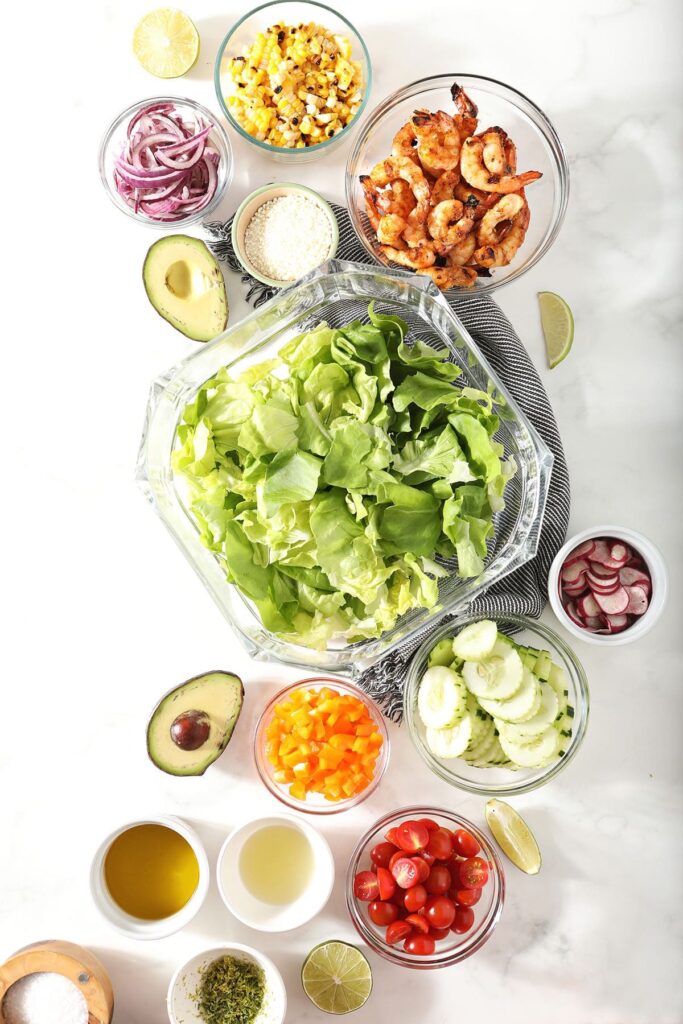 Ingredients to make a salad recipe in bowls on marble