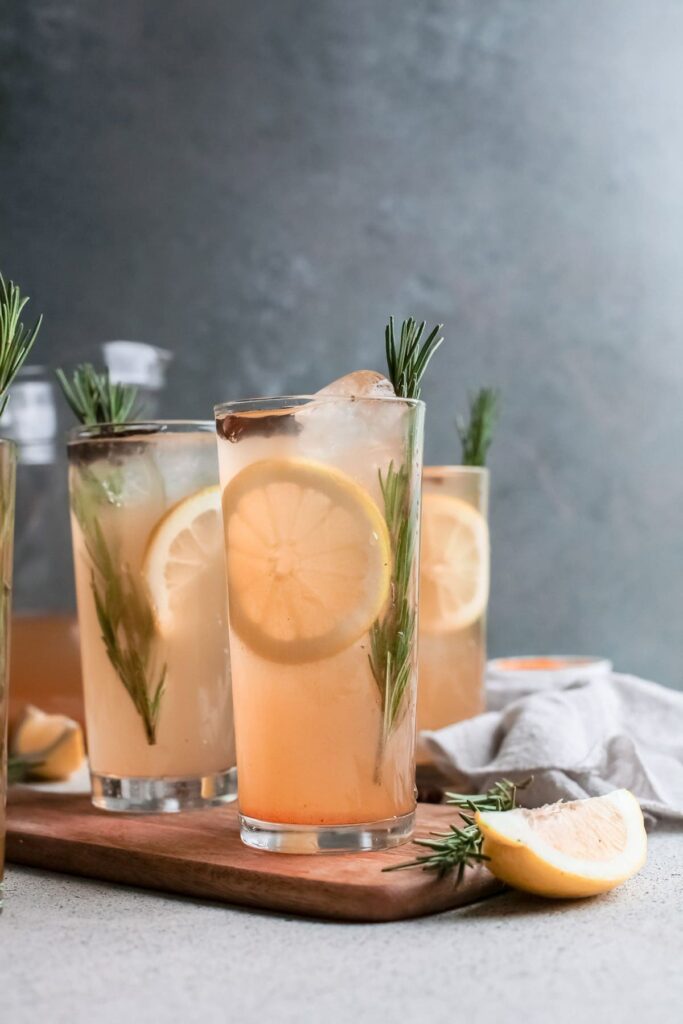 Three pumpkin cocktails on wood garnished with lemon and rosemary