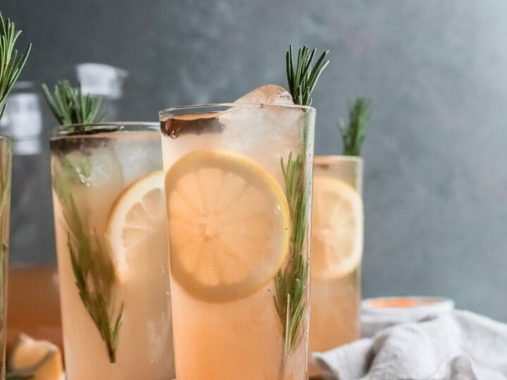 Three pumpkin cocktails on wood garnished with lemon and rosemary