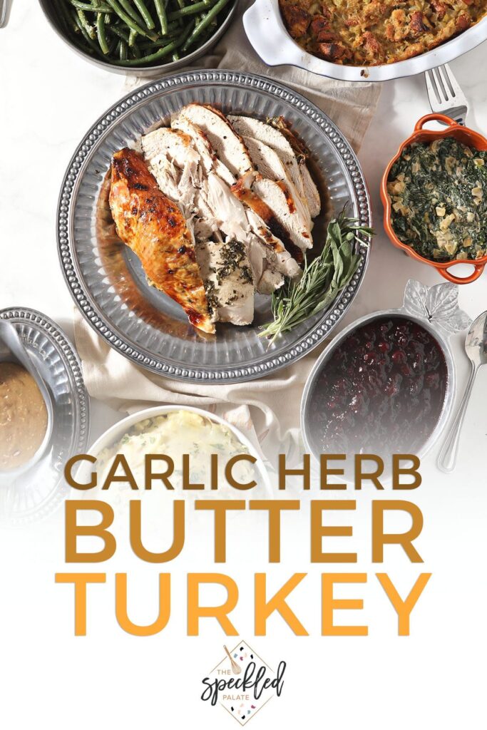 Sliced turkey on a tray with other sides with the text garlic herb butter turkey