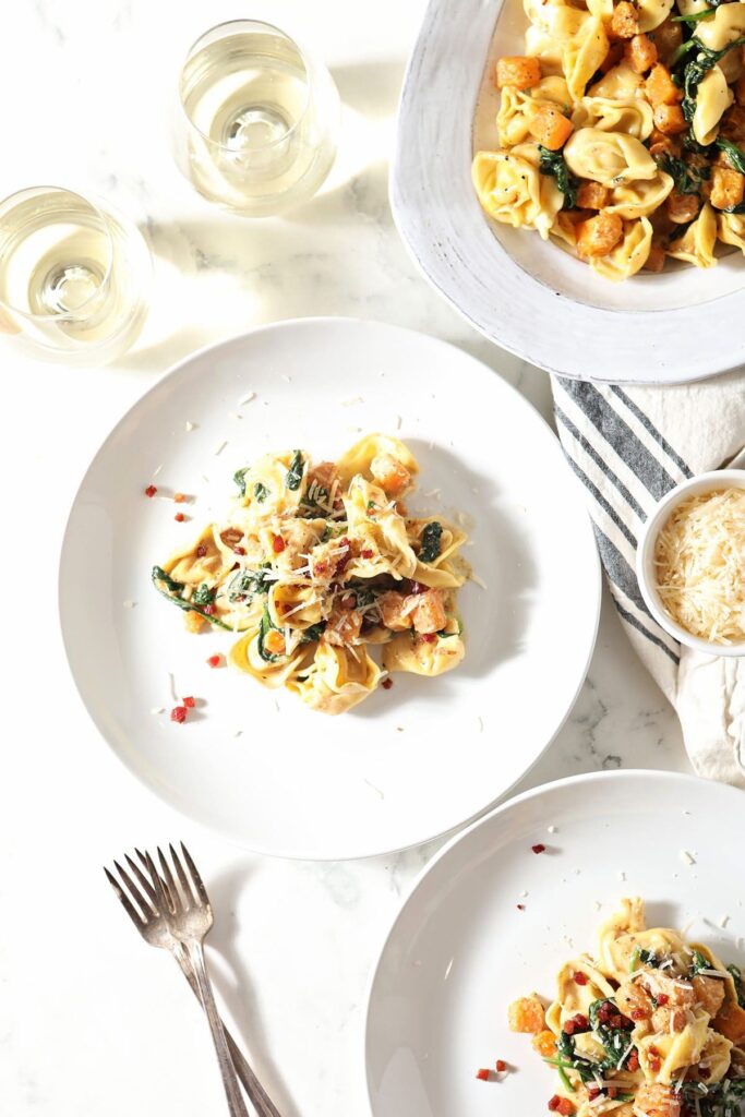 Two servings of butternut squash pasta on white plates