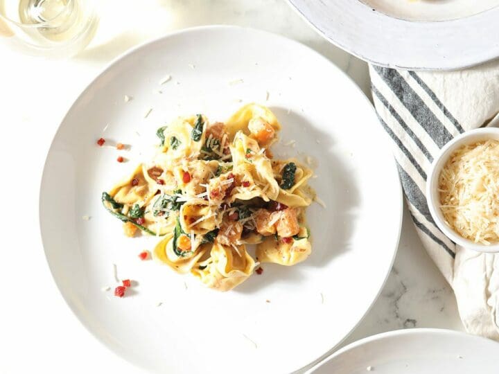 Two servings of butternut squash pasta on white plates