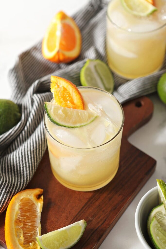 A nonalcoholic margarita on a wooden board with limes and oranges