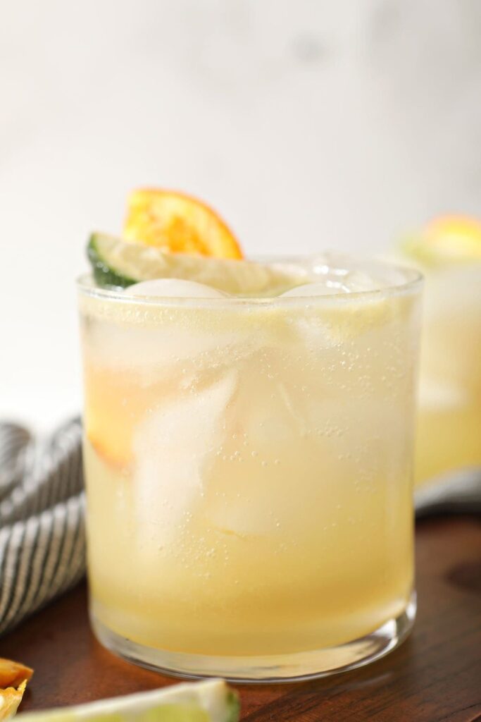 Close up of a yellow mocktail with lime and orange