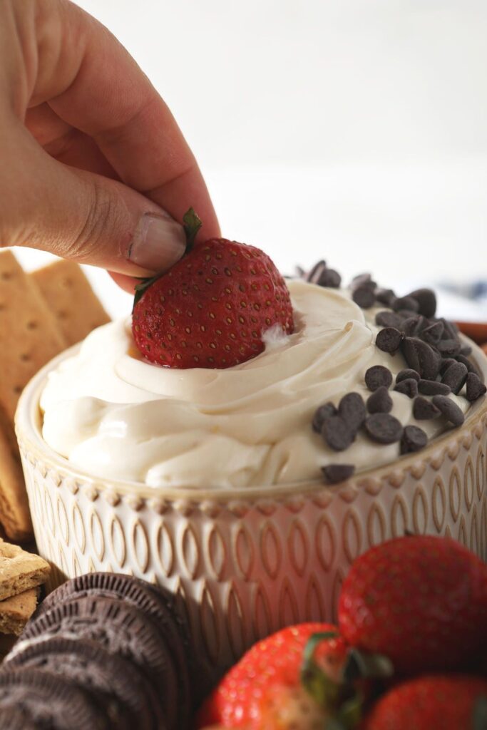 A strawberry dips into cheesecake dip