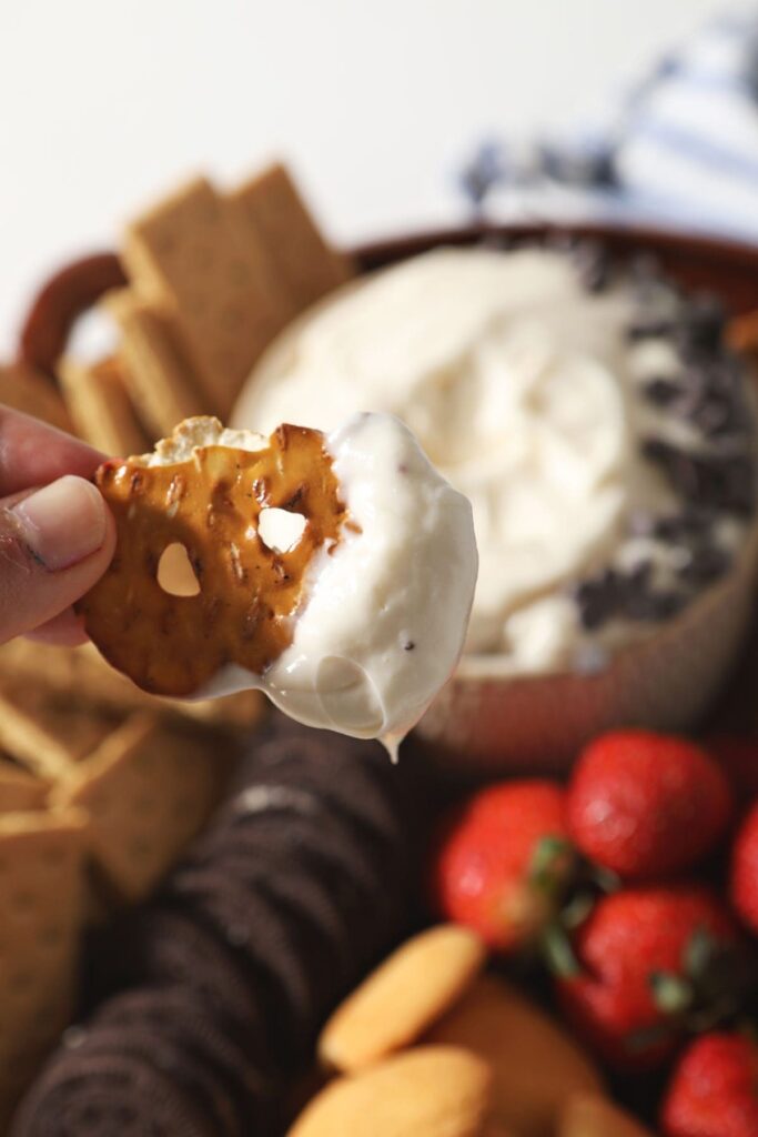 A pretzel holds a bite of cheesecake dip