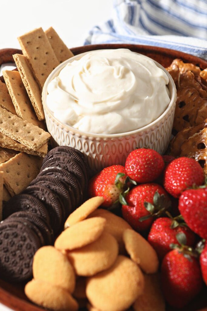 Cheesecake dip in a bowl with cookies, fruit and other dippers