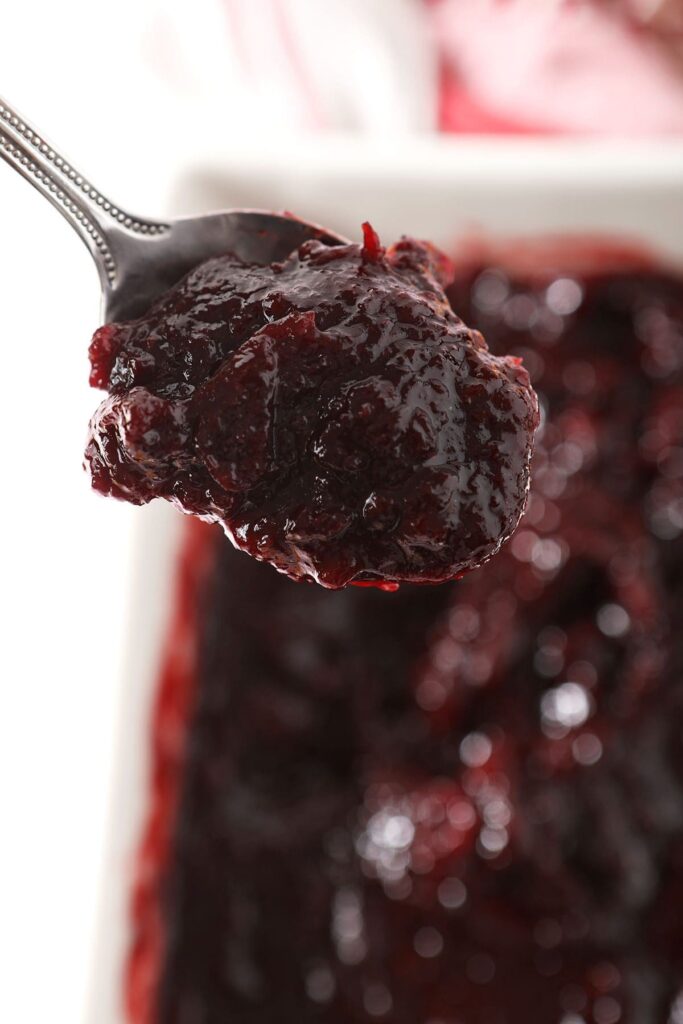 A spoon holds a scoop of a homemade cranberry sauce recipe