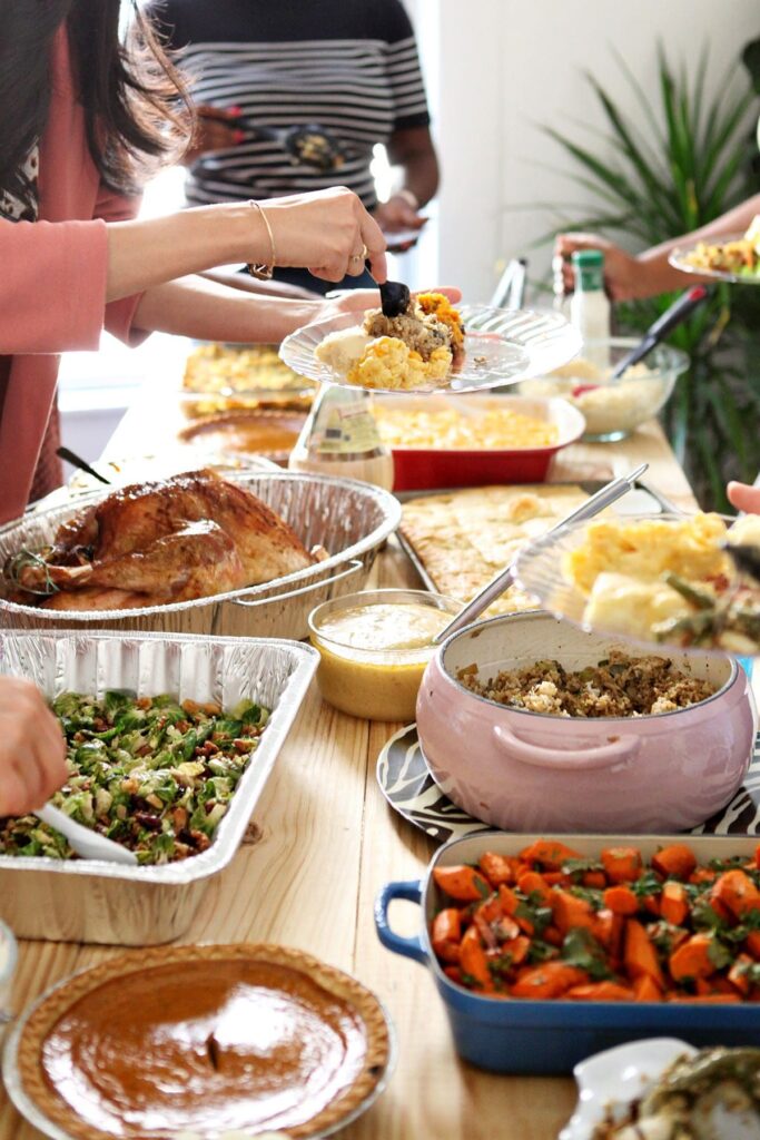 Guests fill their plates with Friendsgiving food on a table