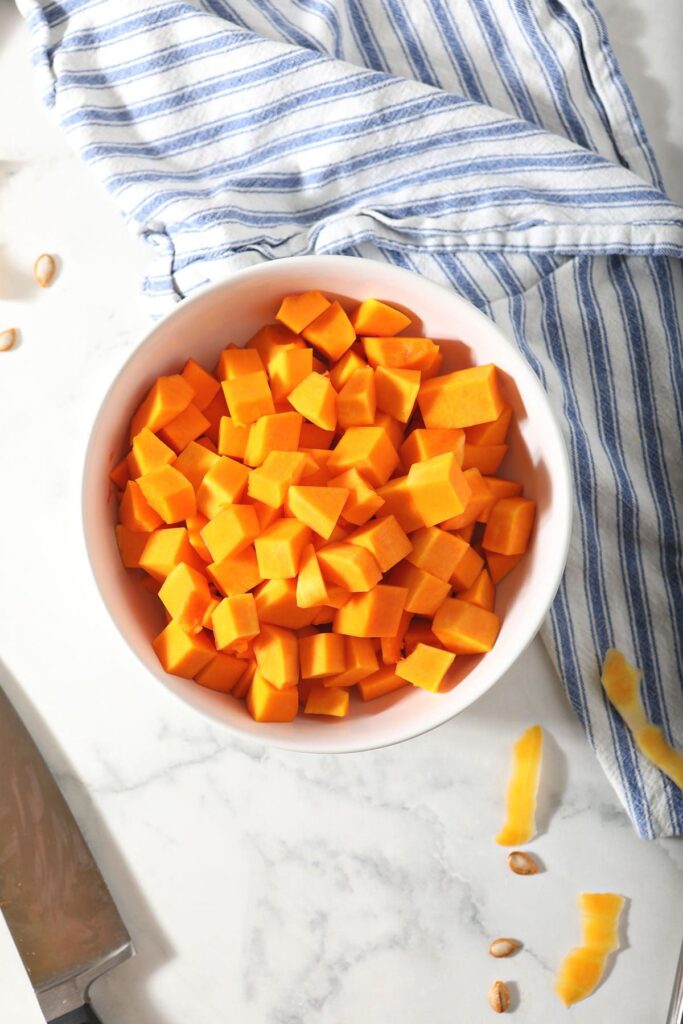 A bowl of chopped butternut squash on marble