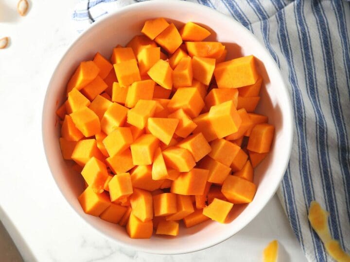 A bowl of chopped butternut squash on marble
