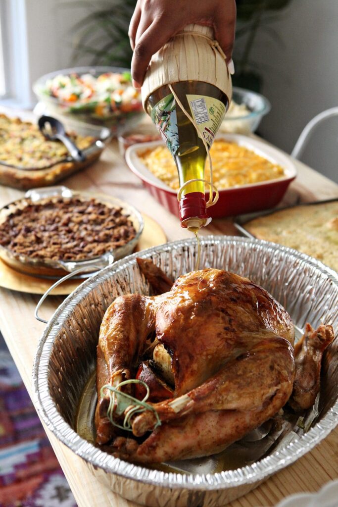 Oil drizzles onto a turkey on a Friendsgiving table