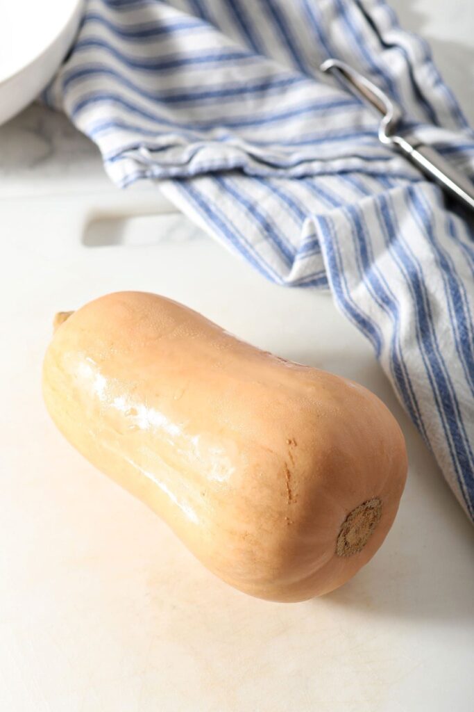 A butternut squash on a white cutting board