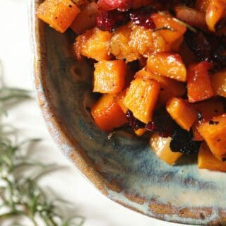 A blue pottery dish holds roasted Maple Cranberry Butternut Squash