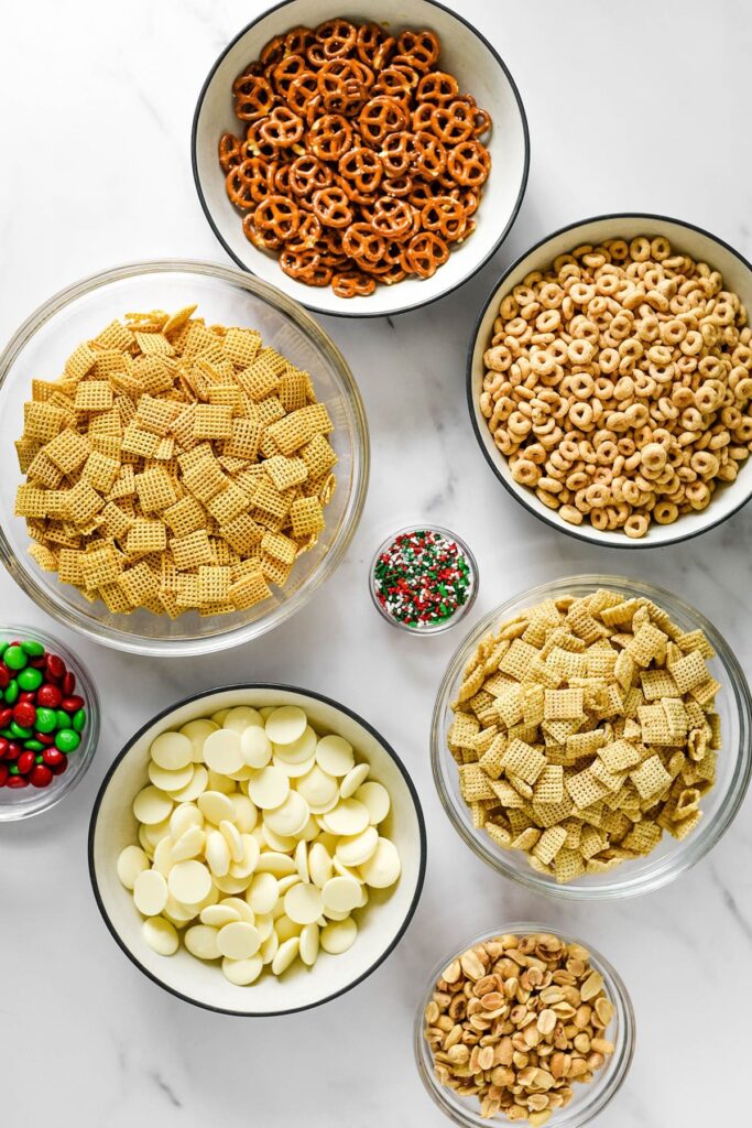 Ingredients for Sweet and Salty Chex Mix recipe in bowls on marble