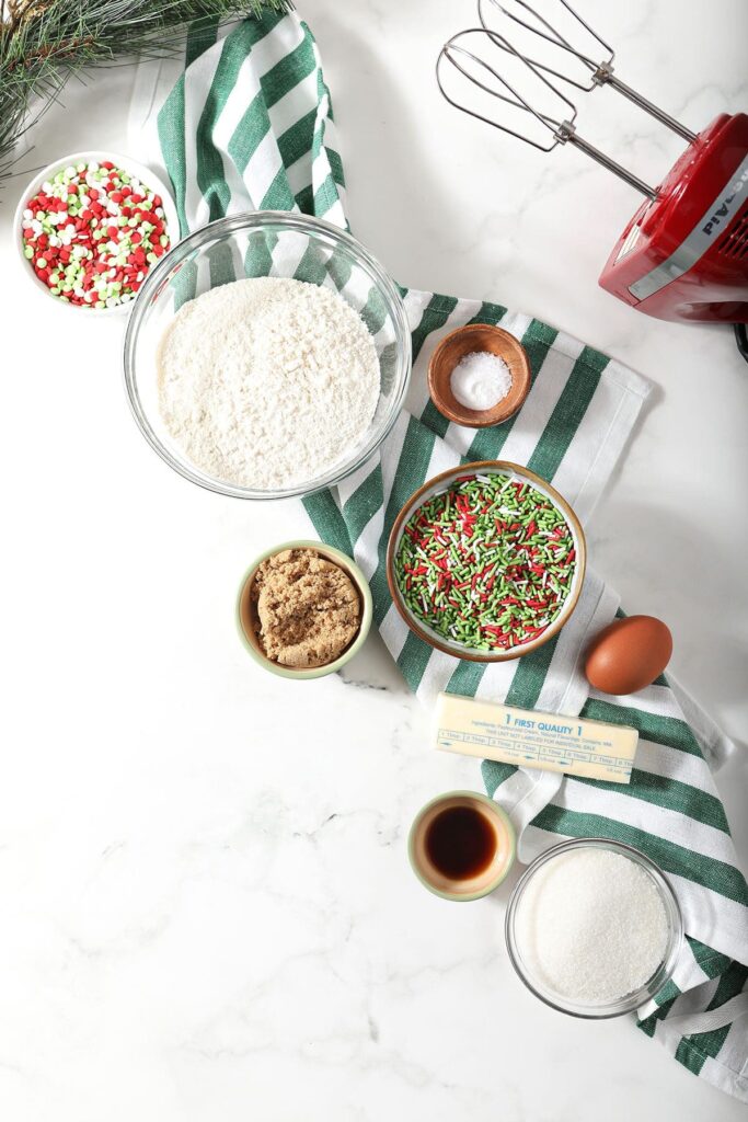 Cookie ingredients in bowls on marble with a green striped towel