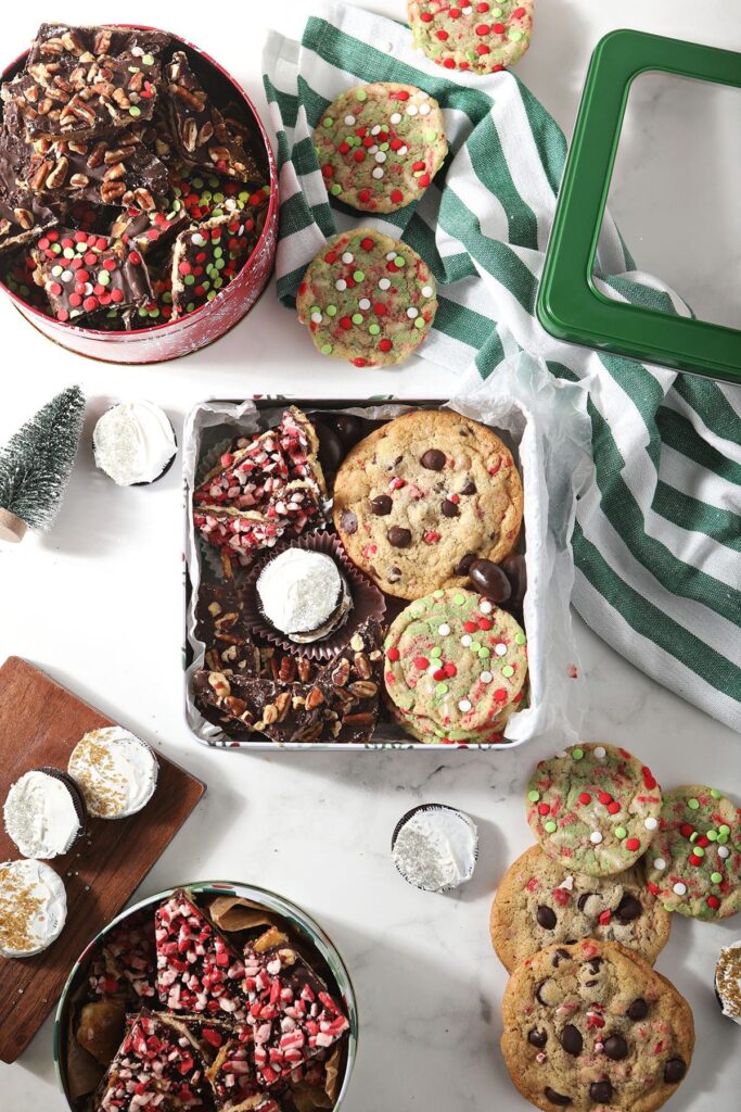 A box of homemade cookies and treats surrounded by cookies on marble