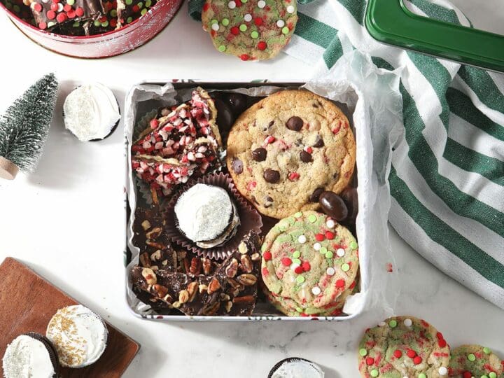 A box of homemade cookies and treats surrounded by cookies on marble