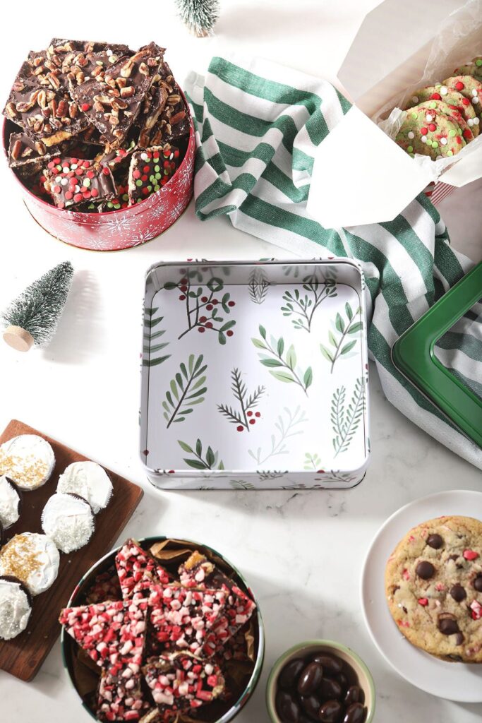 An empty cookie tin surrounded by Christmas cookies