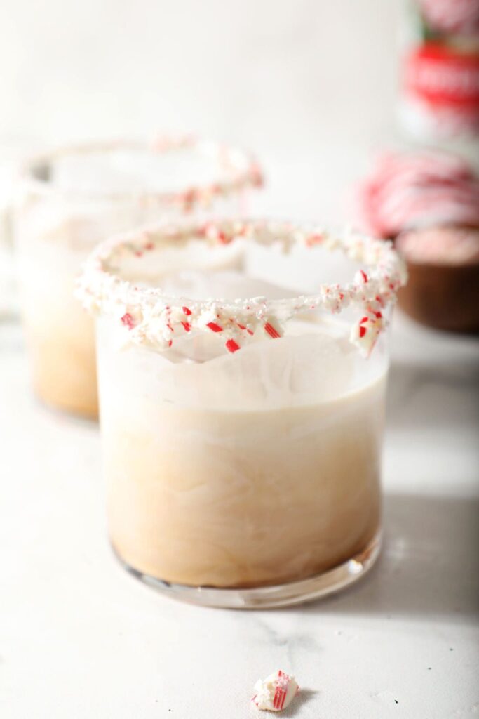 Two peppermint white russian drinks with candy cane rims