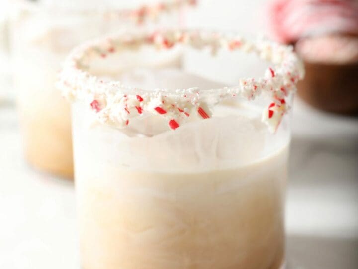Two peppermint white russian drinks with candy cane rims