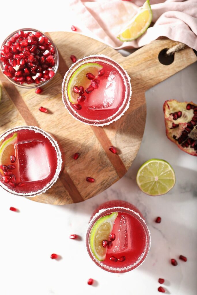 Three pomegranate margaritas from above on marble and wood