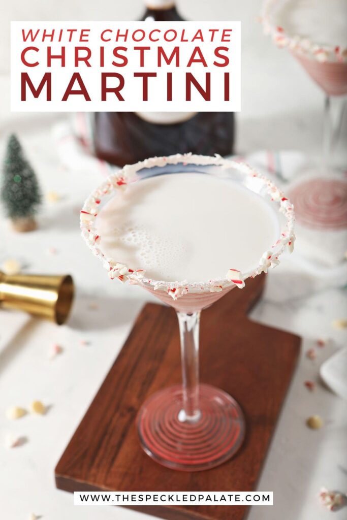 A martini glass rimmed with candy canes on a wood board with the text white chocolate christmas martini