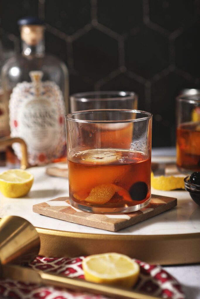 Three amaro cocktails on wooden trivets with lemons