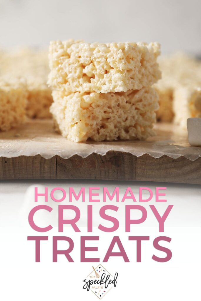 Two rice krispie treats are stacked on top of each other on a cutting board with the text homemade crispy treats